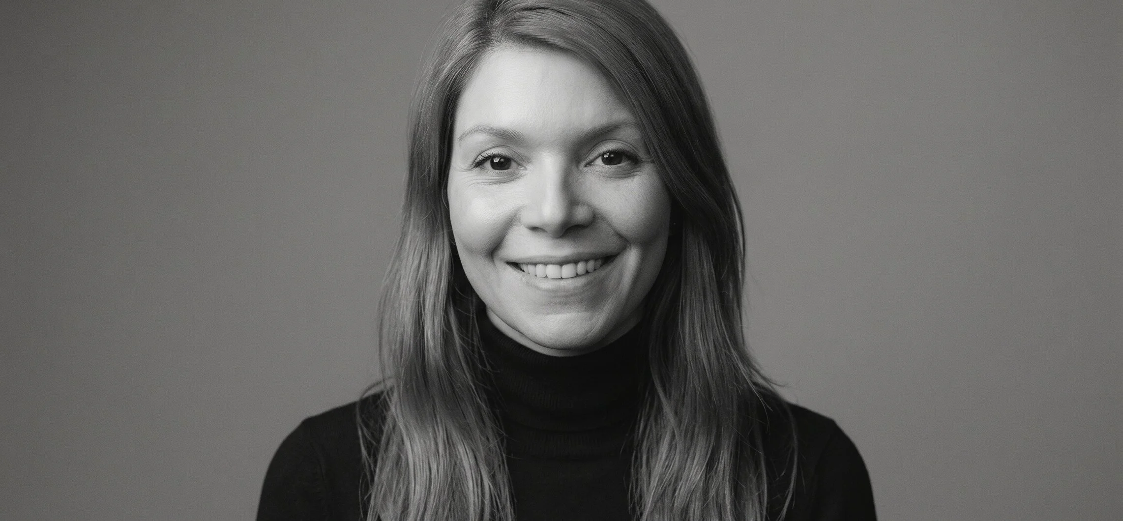 Michelle Protzek — a calm, direct portrait against a quiet studio wall with a framed illustration.